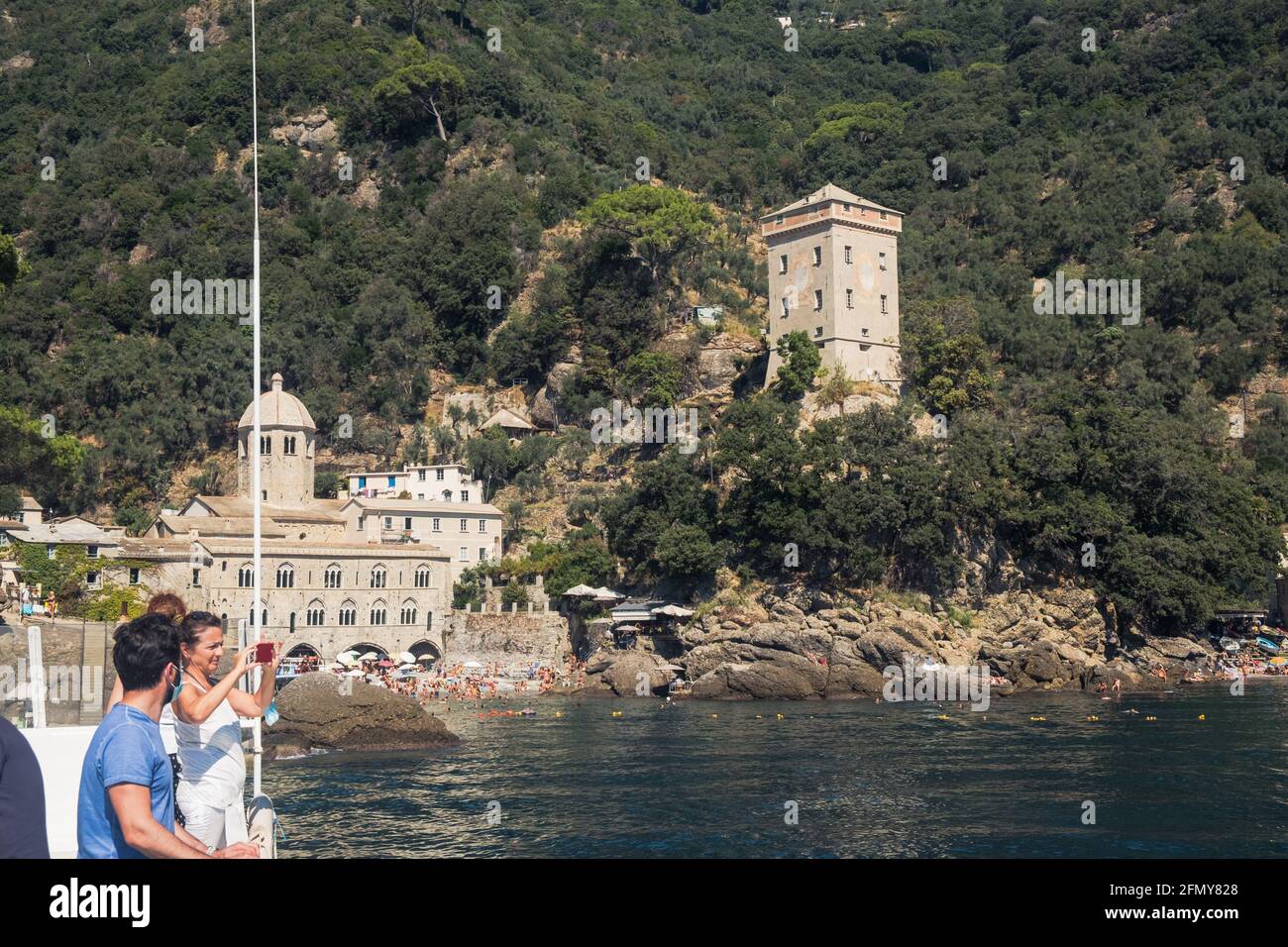 Touristen kommen mit dem Boot an ihr Ziel, die Abtei San Fruttuoso und den nahe gelegenen Doria-Turm in einer geschlossenen Bucht mit einem kleinen Strand. Stockfoto