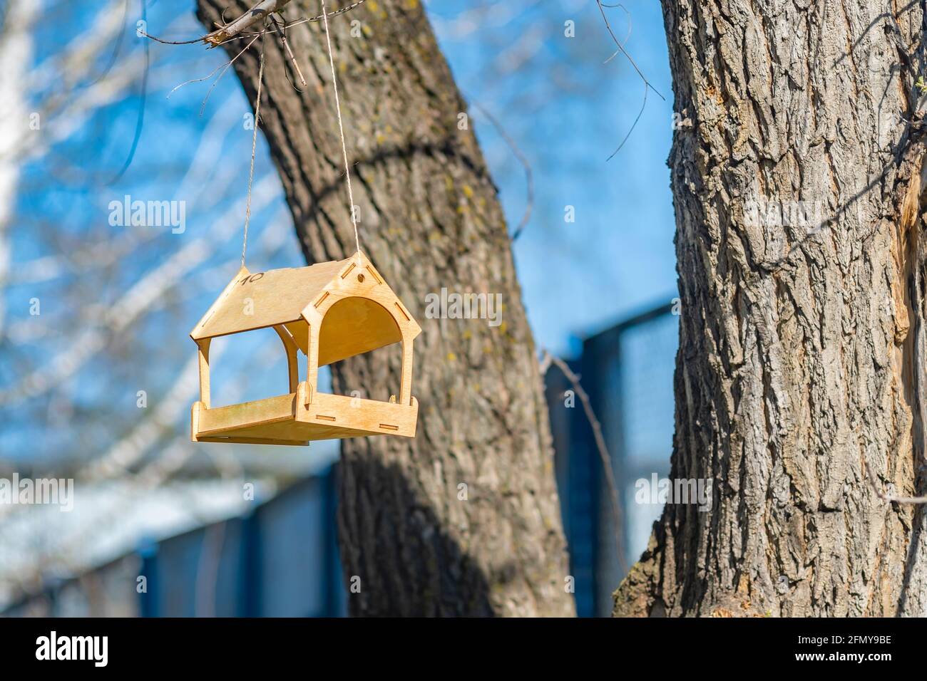 Ein schönes, handgemachtes Vogelfutterhäuschen aus Holz hängt hoch auf einem Baum Stockfoto
