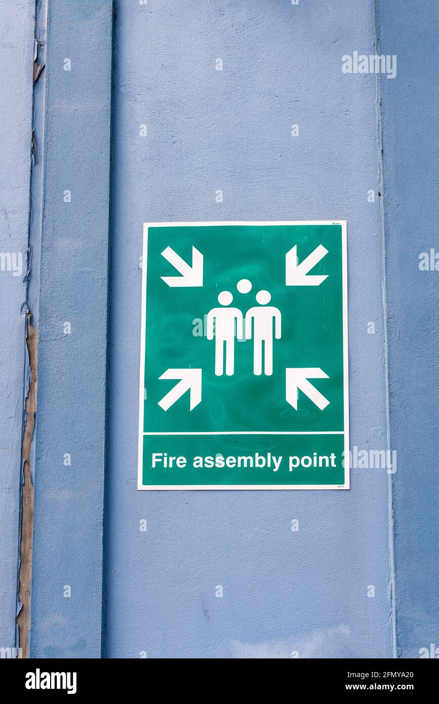 Grünes „Fire Assembly Point“-Schild an einer Fabriktür Stockfoto