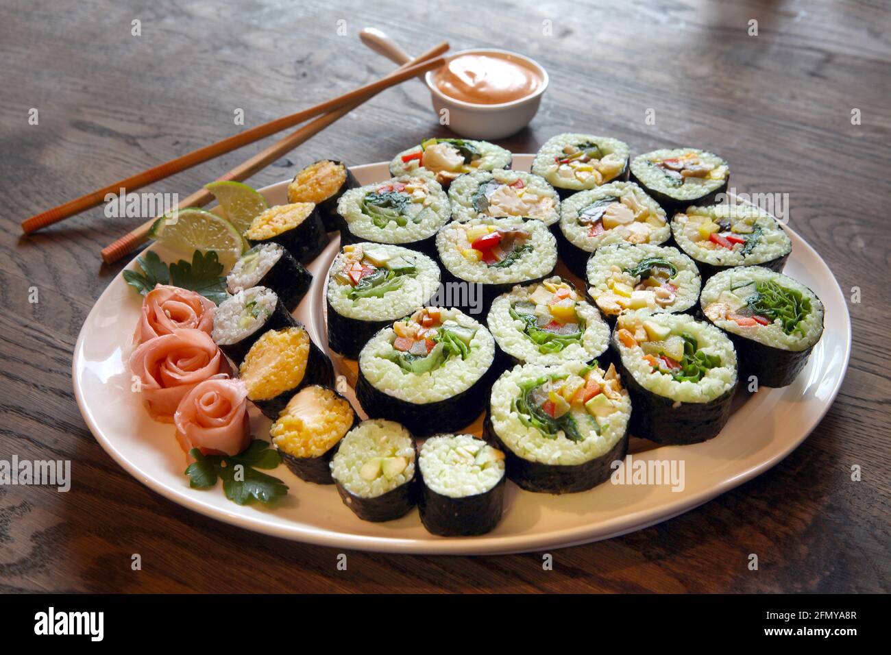 Großes Set mit Sushi und Brötchen. Große Rollensätze auf weißen Tellern auf einem Holzhintergrund. Perspektivische Ansicht Stockfoto
