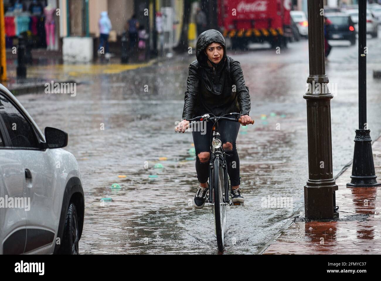 Non Exclusive: TOLUCA, MEXIKO - MAI 12: Eine Frau fährt auf einem Fahrrad mit Regenmantel bedeckt, da die Stadt mit starken Regenfällen dämmerte und mehr Regenfälle sind Stockfoto