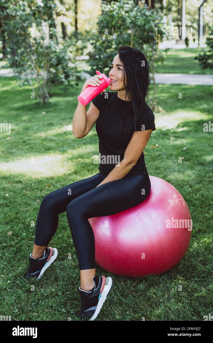 Junge fit gebräunte Frau Athlet trinkt Protein-Shake nach dem Training im Freien. Sporternährung. Weicher, selektiver Fokus. Stockfoto