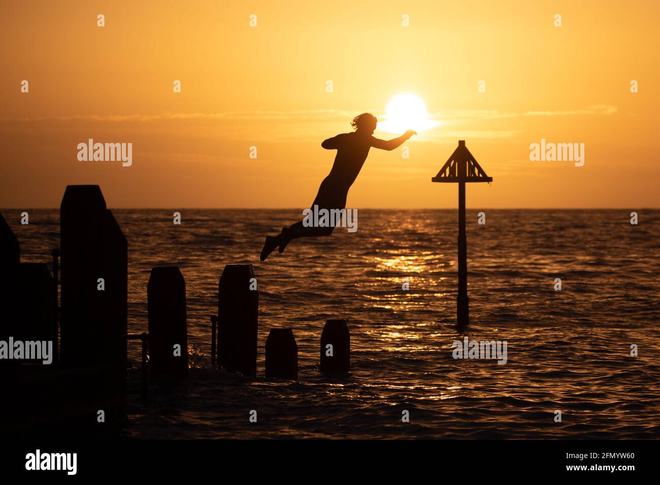 Aberystwyth, Ceredigion, Wales, Großbritannien. Mai 2021. UK Wetter: Eine Person, die vom Steg in Aberystwyth taucht, während die Sonne über der Westküste untergeht. Kredit: Ian Jones/Alamy Live Nachrichten Stockfoto