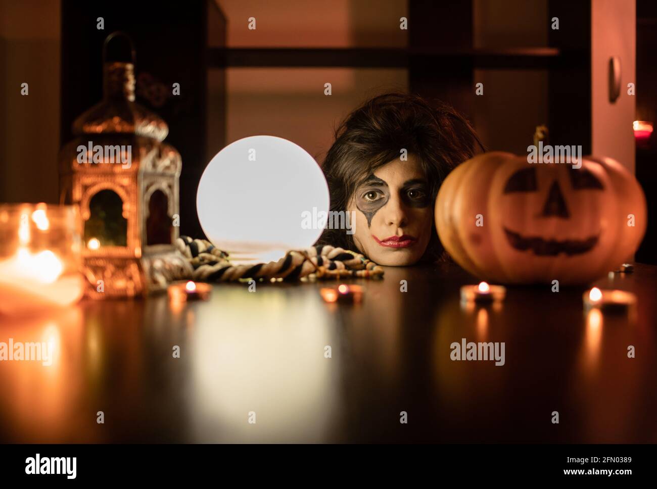 Halloween Hexe mit Kürbis und magischen Lichtern. Junges und lustiges Mädchen mit halloween Make-up und Kostüm bereit für die Party. Stockfoto