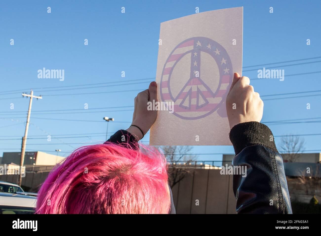 Protestler mit rosa Haaren hält handgemachte Frieden Symbol Zeichen - Bild von hinten sichtbar, wie Licht durch Zeichen scheint Stockfoto