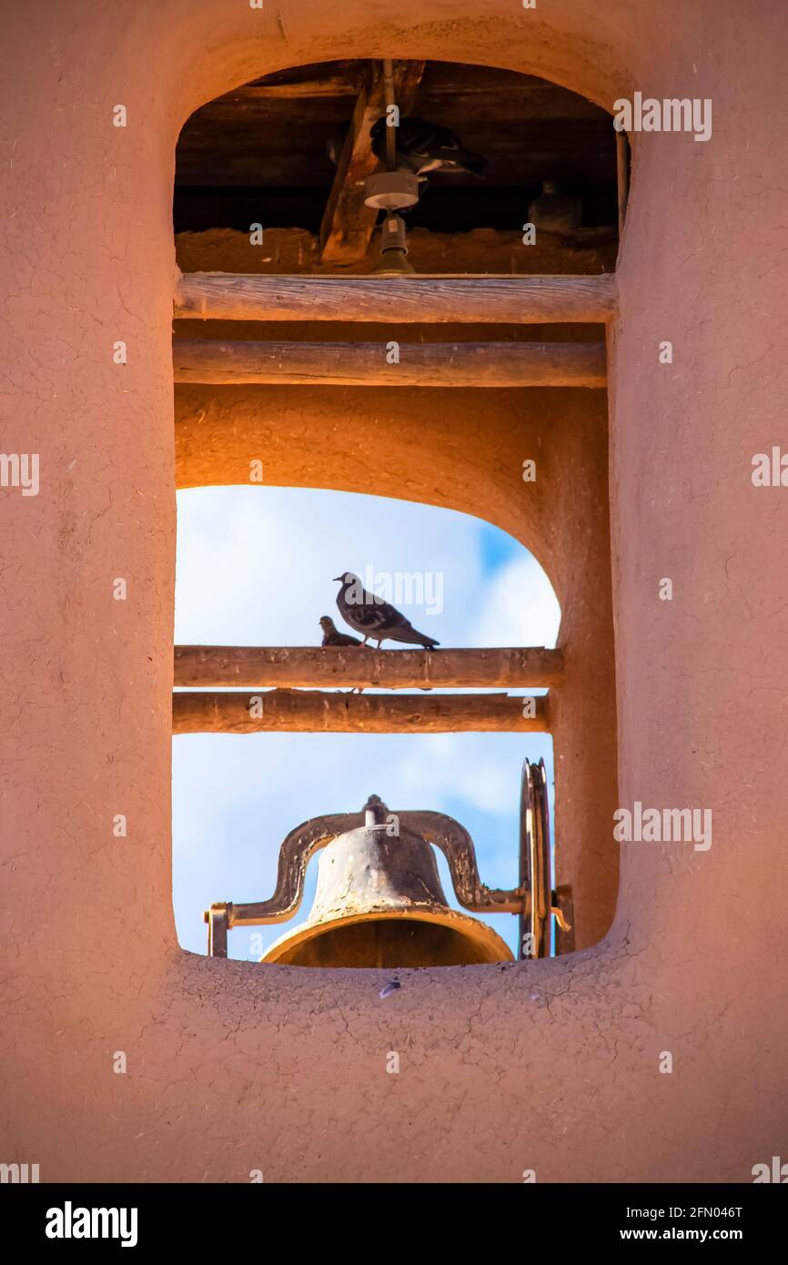 Vögel, die im Glockenturm der adobe-Missionskirche stehen Amerikanischer Südwesten mit blauem Himmel, der durchleuchtet - selektiver Fokus Nahaufnahme Stockfoto