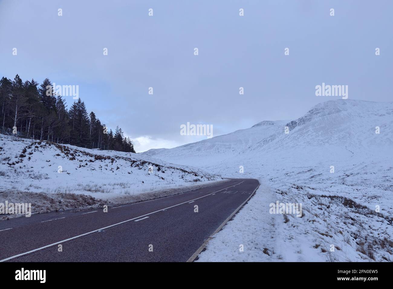 Gebogene leere Straße auf verschneiten Bergen im winter in schottland. Skye Island Stockfoto