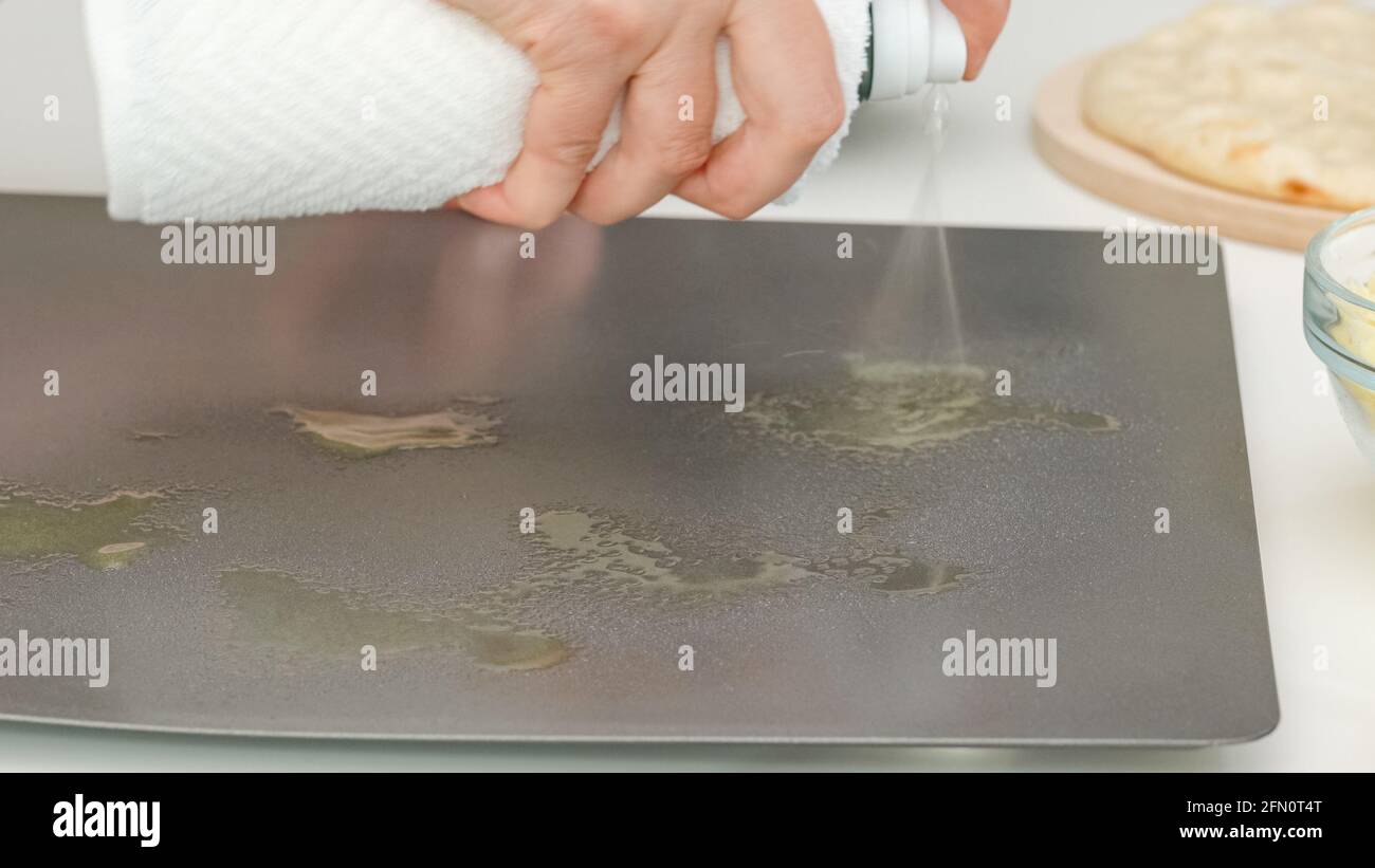 Frau mit Olivenöl Spray auf der Backform. PizzaSchritt für Schritt Backprozess, Rezept Stockfoto
