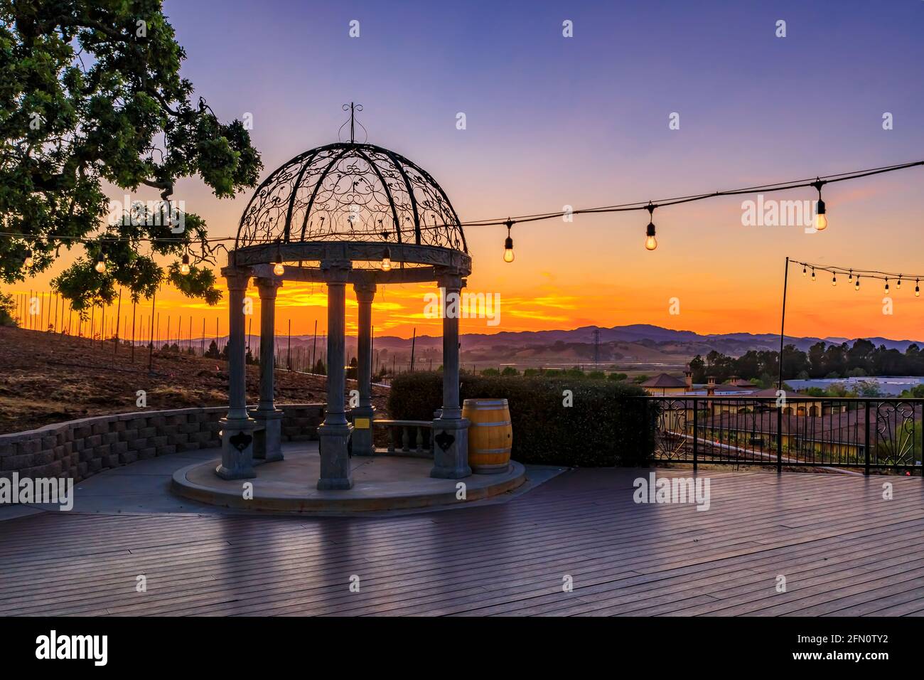 Im Freien Stühle und Tisch auf einer Holzterrasse bei Sonnenuntergang im Frühjahr mit Weinreben und Hügeln im Hintergrund, Napa Valley, Kalifornien, USA Stockfoto