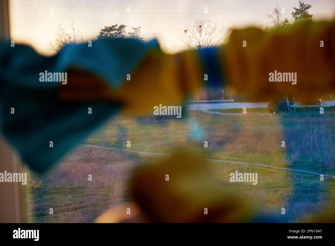 Frühjahrsputz-Konzept. Desinfizieren und reinigen durch die Pandemie, covid 19. Blaugrün und orange. Die Hand wascht das Fenster zu Hause bei Abendlicht. Reflexionseffekt. Speicherplatz kopieren. Selektiver Fokus Stockfoto