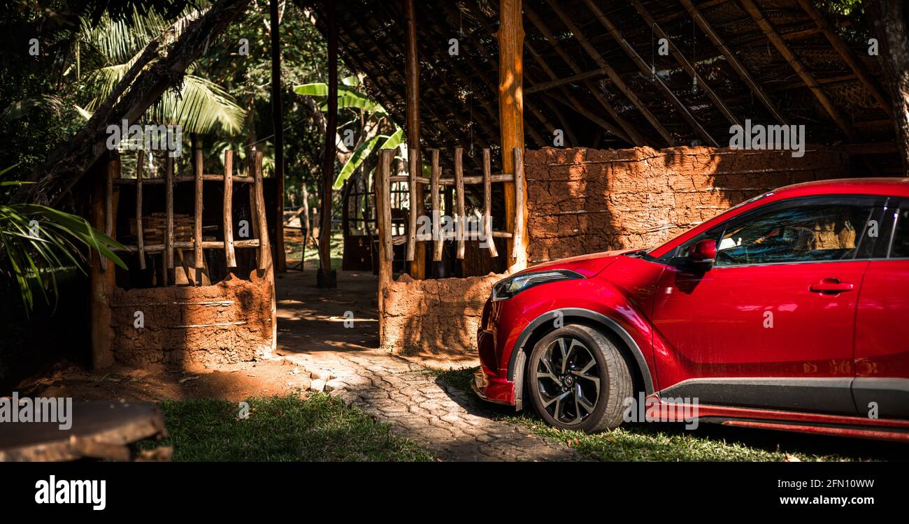 Reetgedeckten Dorfhaus und ein modernes Auto in der Nähe der Eingangstür geparkt. Stockfoto