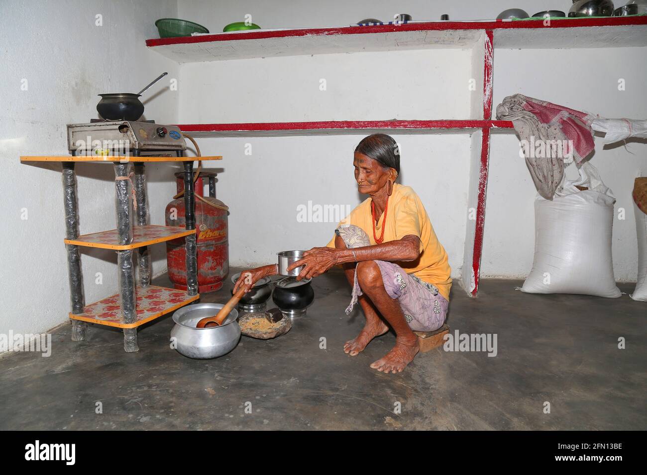 Stammes alte Frau kocht Essen in der Küche. LANJIA SAORA STAMM. Puttasingh Village, Odisha, Indien Stockfoto