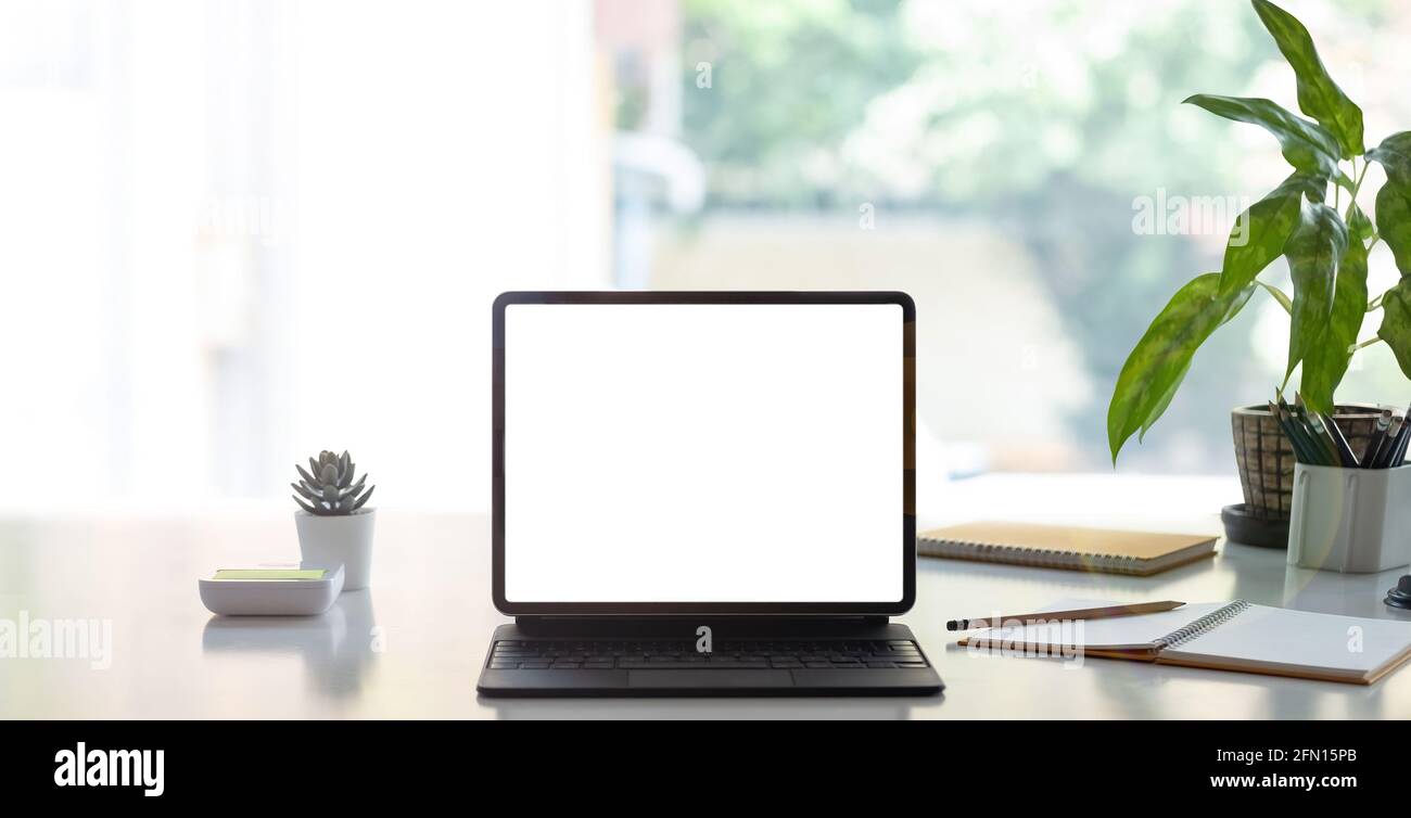 Digitales Tablet mit weißem leeren Bildschirm auf dem Tisch. Arbeitsplatz im modernen Bürokonzept. Stockfoto