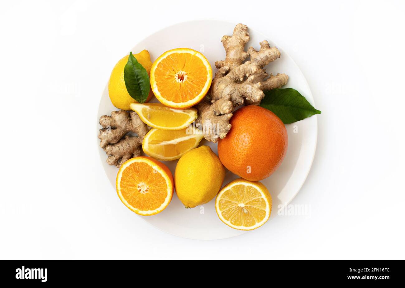 Zitrusfrüchte auf einem weißen Teller, Orangen, Zitronen und Ingwer auf einem weißen Teller auf weißem Hintergrund. Stockfoto