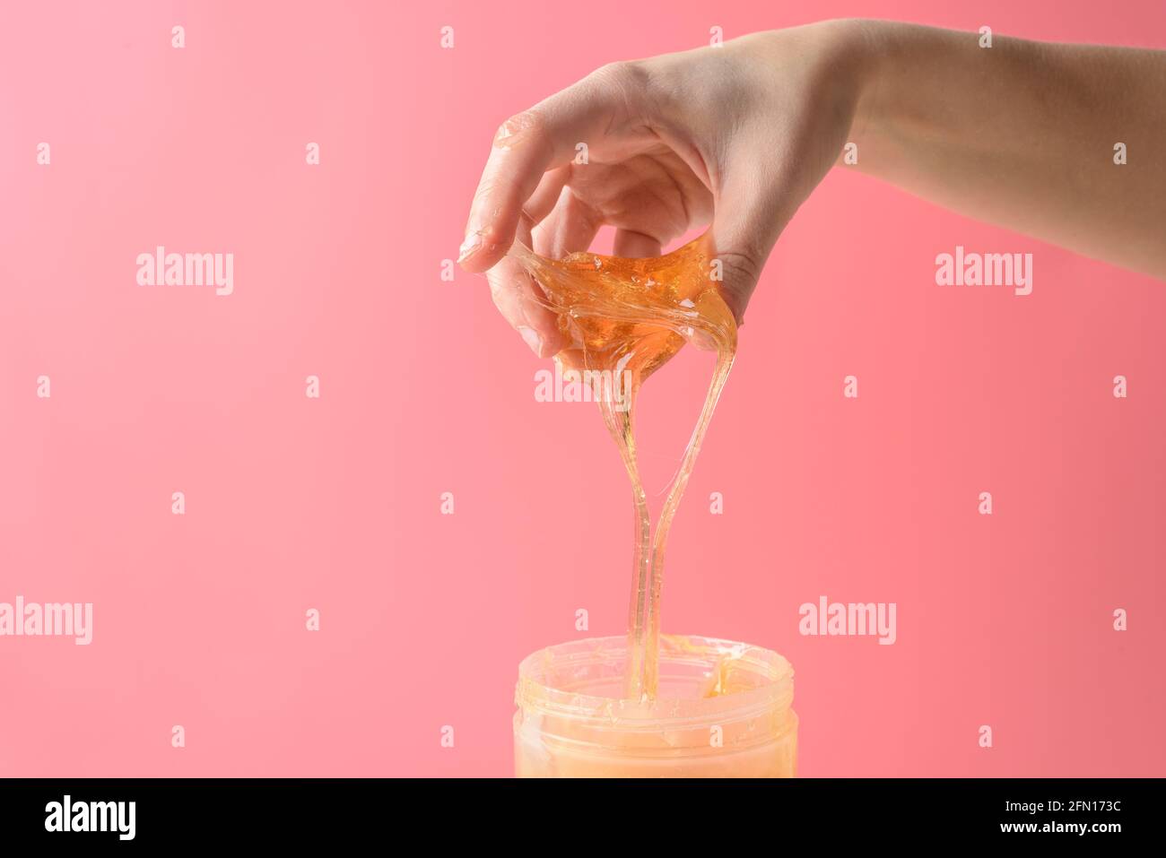 Hand mit Zuckerwachs Stück aus Glas auf rosa Stockfoto