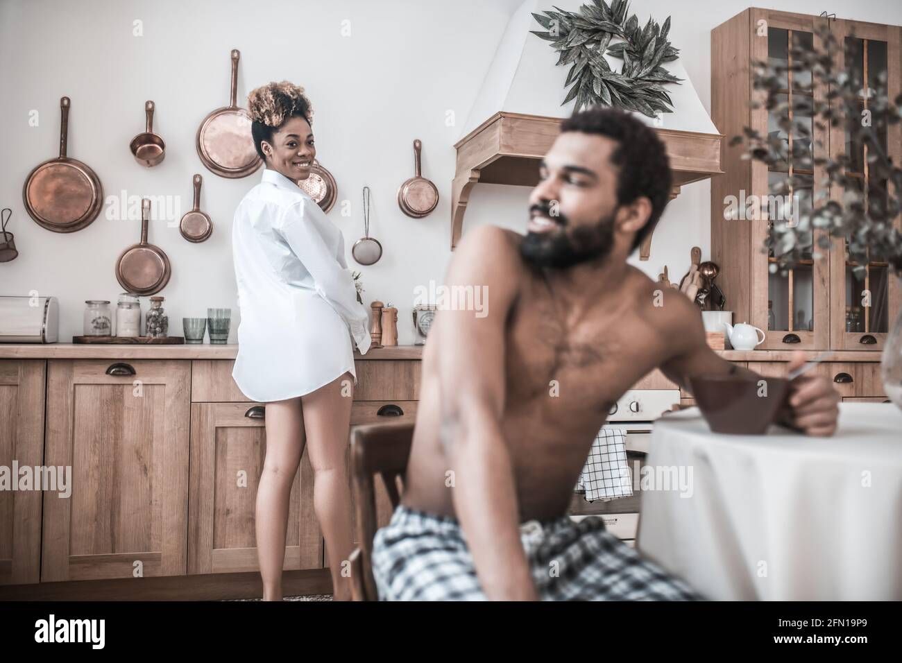Fröhliche Frau, die den Kopf dreht und den Ehemann beim Essen ansieht Stockfoto