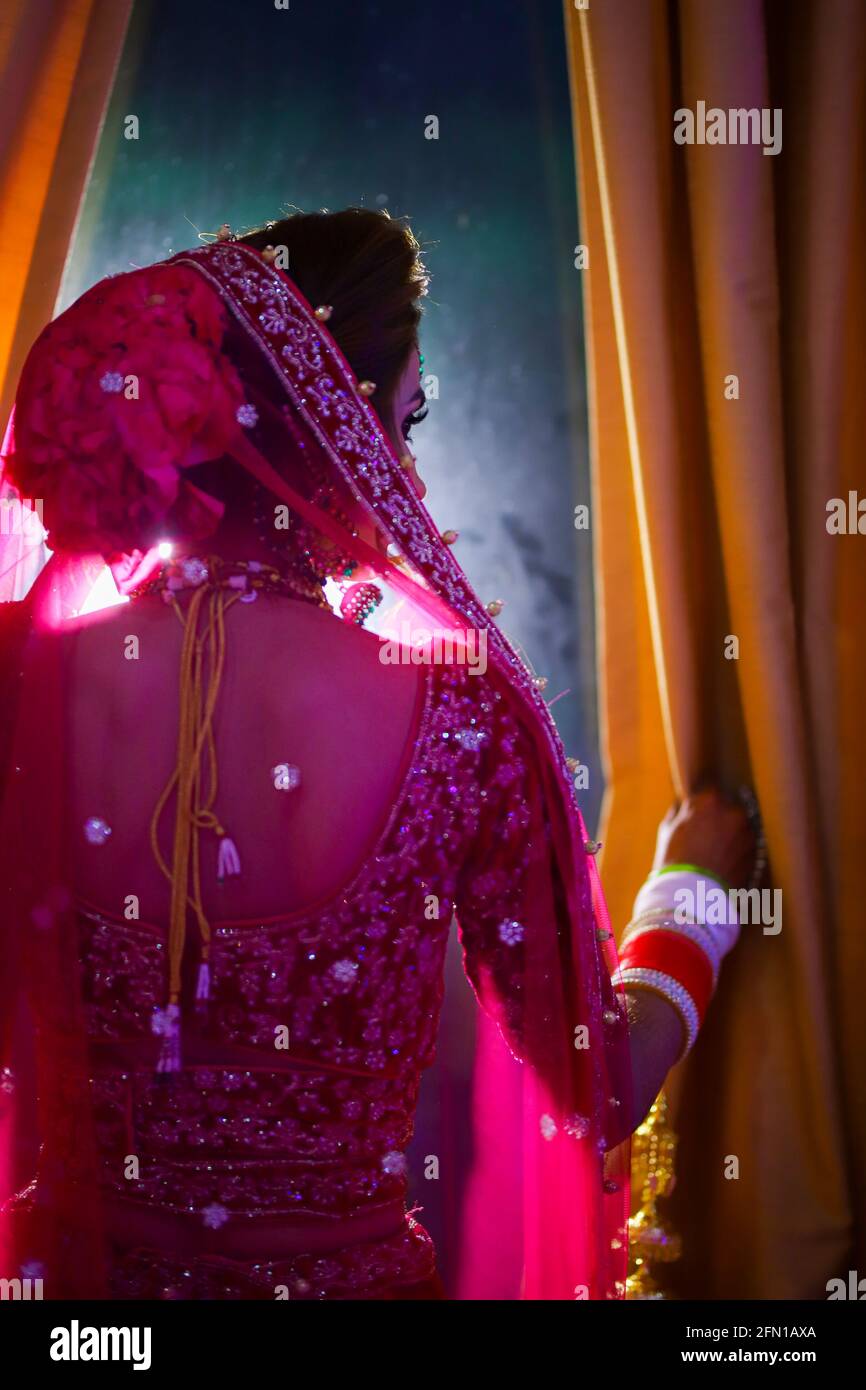 Atemberaubende indische Braut in hindurot gekleidet traditionelle Hochzeitskleidung mit Make-up und Schmuck. Stockfoto