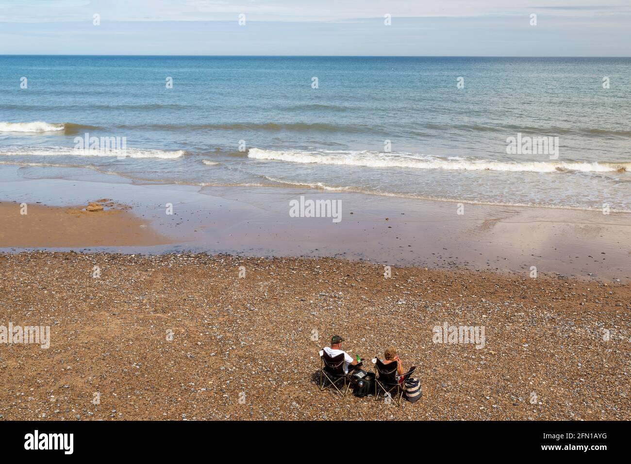 Isoliertes Paar (in COVID-19-mal), das in Einsamkeit am Strand von Overstrand, Norfolk, Großbritannien, saß Stockfoto