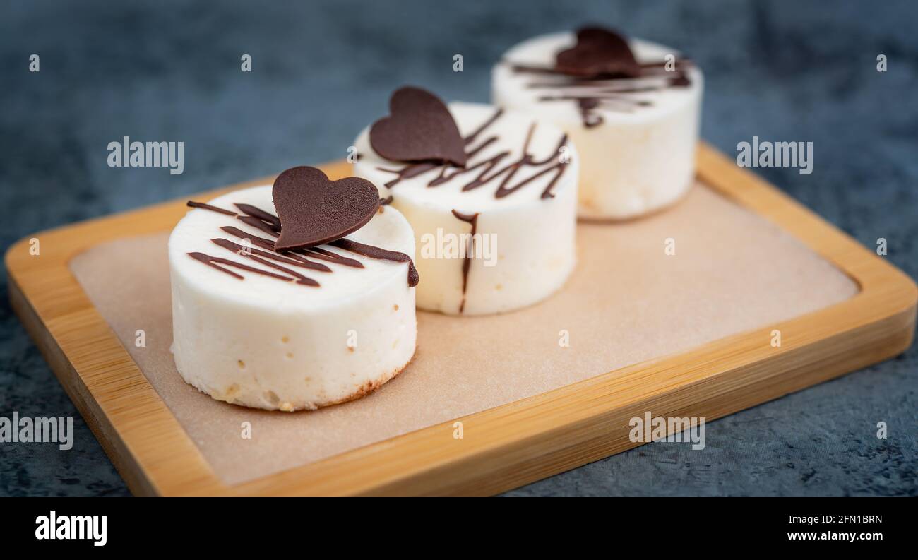 Mini-Kuchen mit einem Schokoladenherz auf einem Holztablett Stockfoto