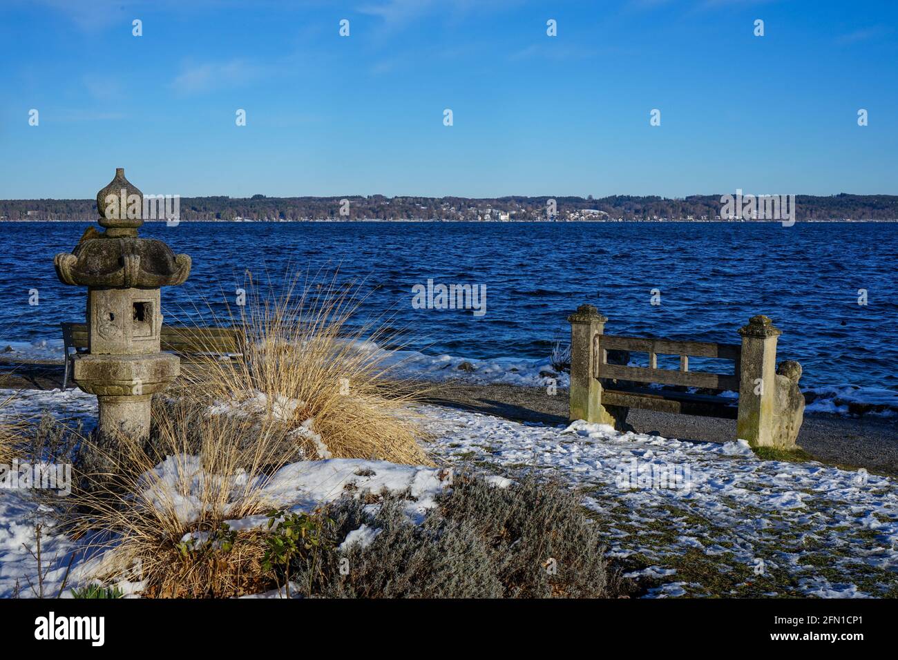 Blick auf einen See. Am Ufer gibt es eine Steinbank und eine Skulptur. Stockfoto