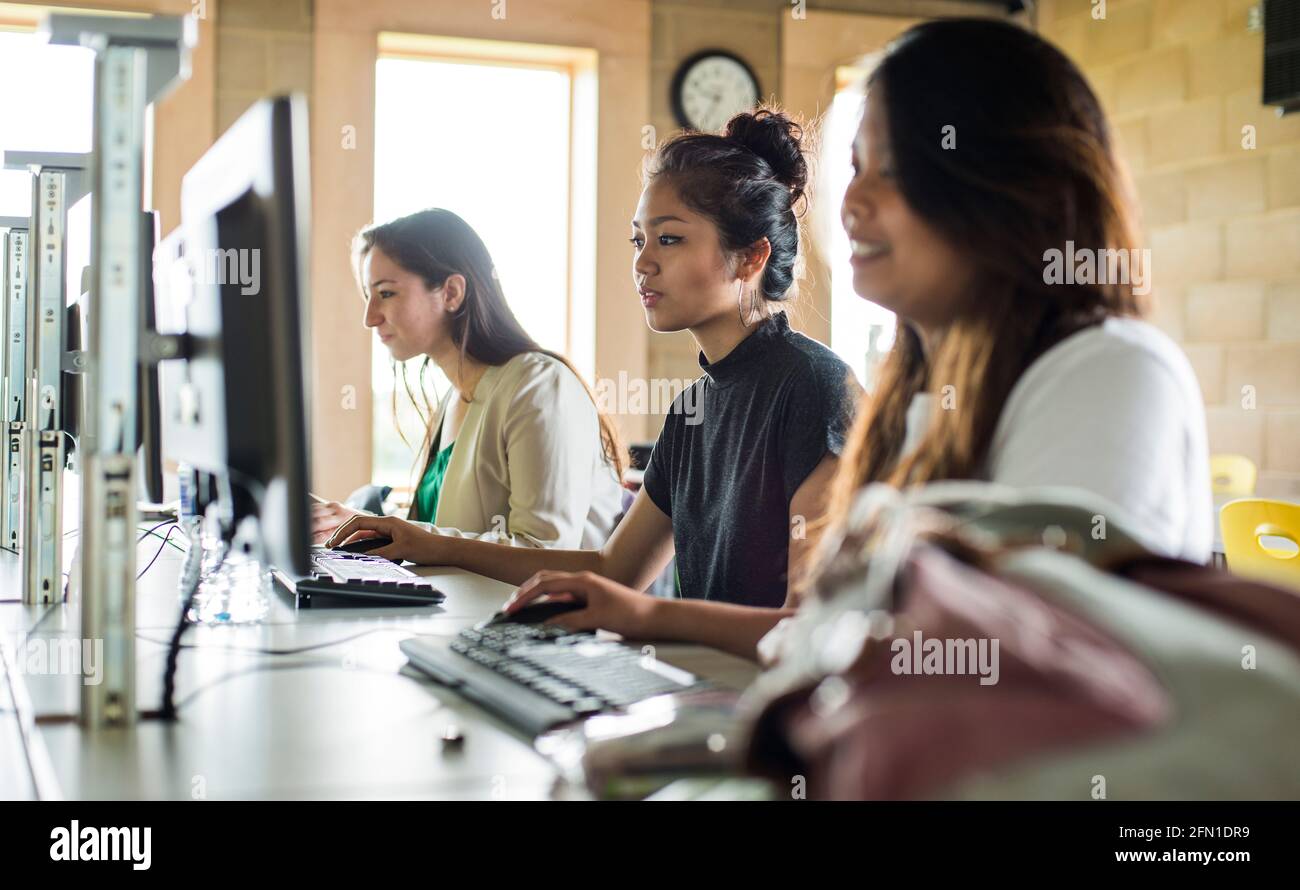 Sechste Schulstufe Studenten, junge Erwachsene im Bildungsbereich, multikulturelle Mädchen in sechster Schulstufe am Computerbildschirm, gemischte Mädchen in sechster Schulstufe Stockfoto