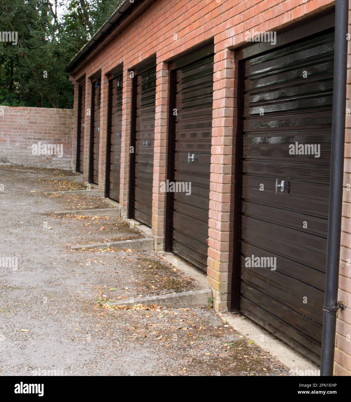 Ein Block moderner, unscheinbarer Garagen mit frisch lackiertem Schwarz Metalltüren Stockfoto
