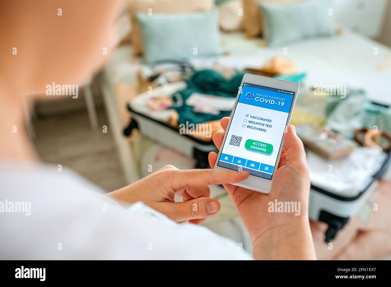 Frau, die den Koffer vorbereitet und digital grün Pass auf Das Handy Stockfoto