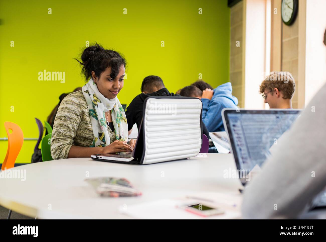 Weibliche schwarze Studentin der sechsten Schulstufe, junge Frau im britischen Bildungswesen, Teenager-Mädchen, die einen Laptop betrachtet, indische Studentin, die am Laptop arbeitet, Studentin Stockfoto