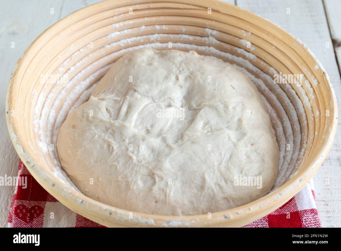 Hausgemachtes Sauerteig-Brot herstellen - den Teig in einem Rohrbaneton beweisen. Stockfoto