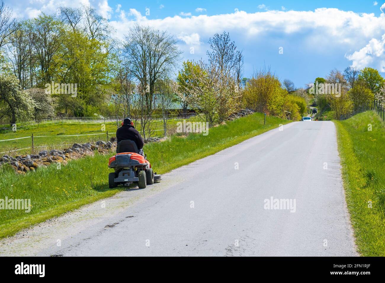 Mann auf einem Aufsitzmäher auf einer Landstraße Stockfoto