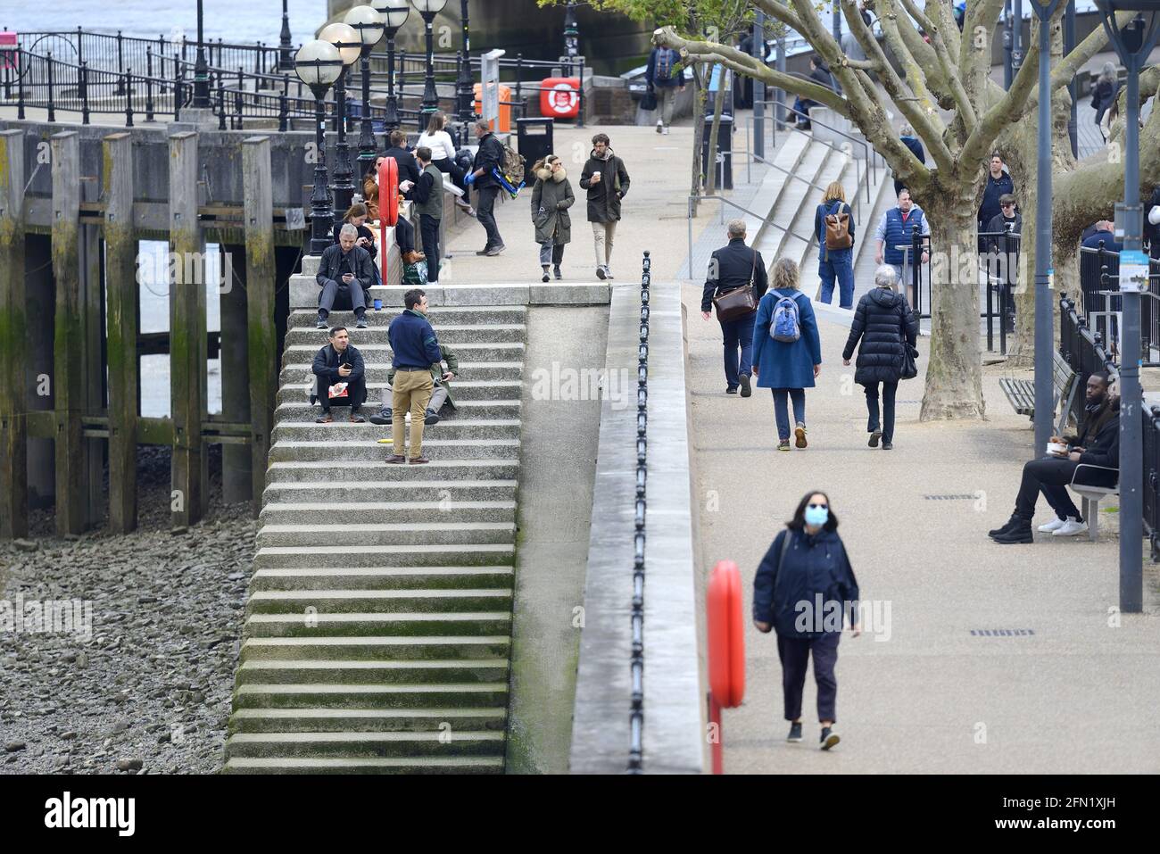 London, England, Großbritannien. Menschen, die am Südufer entlang gehen und auf den Stufen zur Themse sitzen Stockfoto