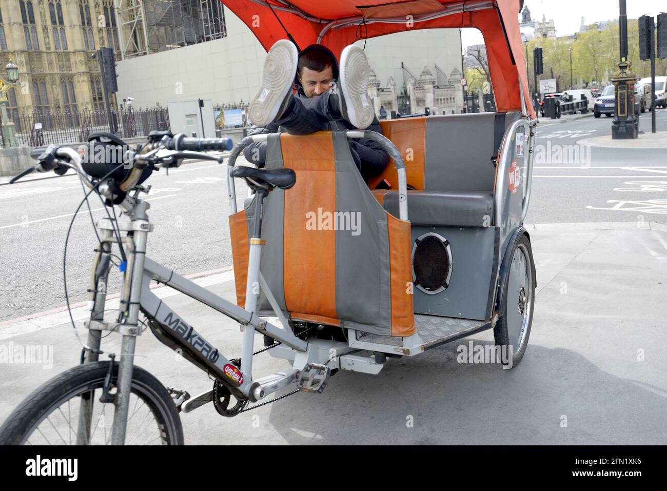 London, England, Großbritannien. Fahrrad-Rikscha/Pedikab-Fahrer, der sich auf der Westminster Bridge entspannt Stockfoto