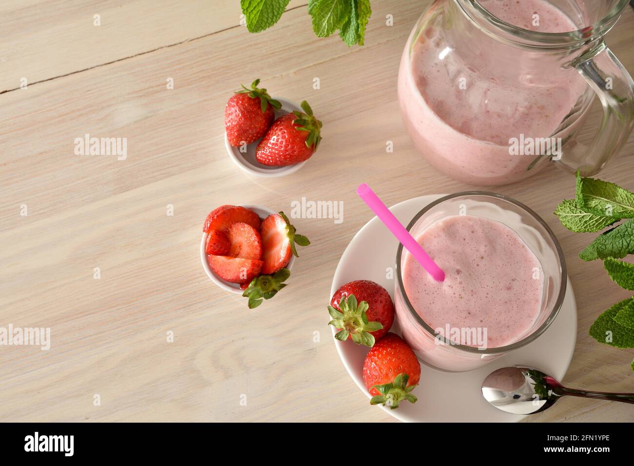 Glas und Krug mit Erdbeer-Smoothie auf Holztisch mit Behältern mit Früchten. Ansicht von oben. Stockfoto