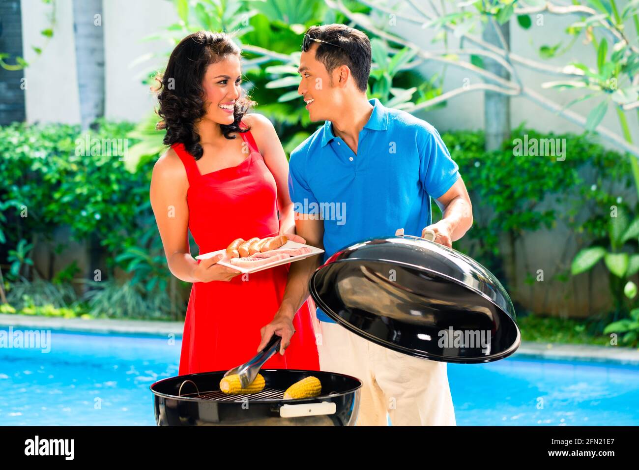 Asiatische hübsches Paar, Grillparty oder Grill draußen am Pool mit gegrillten Maiskolben Stockfoto