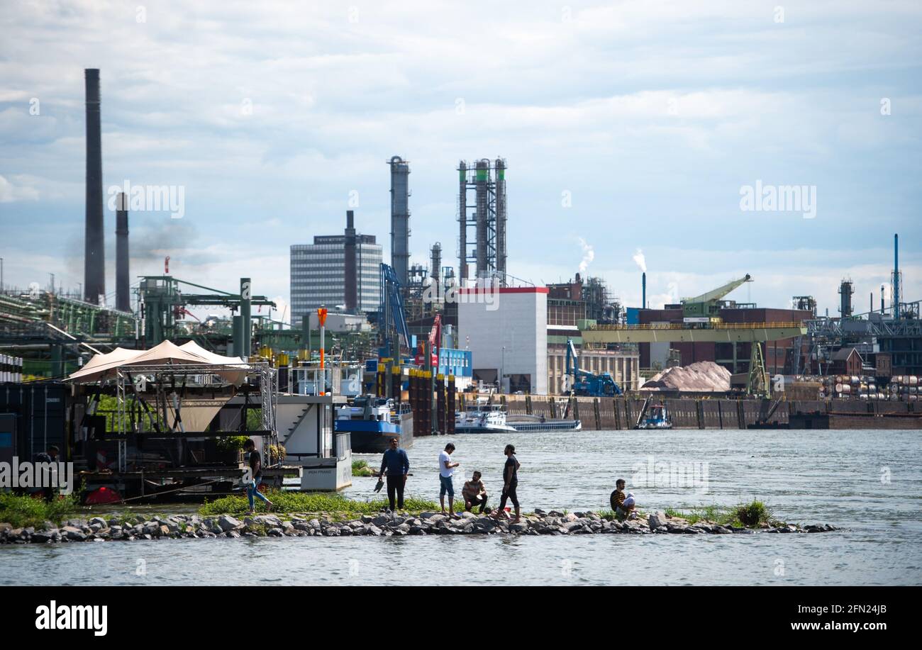 Leverkusen, Deutschland. Mai 2021. Sechs junge Männer sitzen am Rhein, im Hintergrund ist der Chempark zu sehen. Leverkusen zählt mit über 200 Inzidenz weiterhin zu den Ländern mit der höchsten Inzidenz in Nordrhein-Westfalen. Quelle: Jonas Güttler/dpa/Alamy Live News Stockfoto