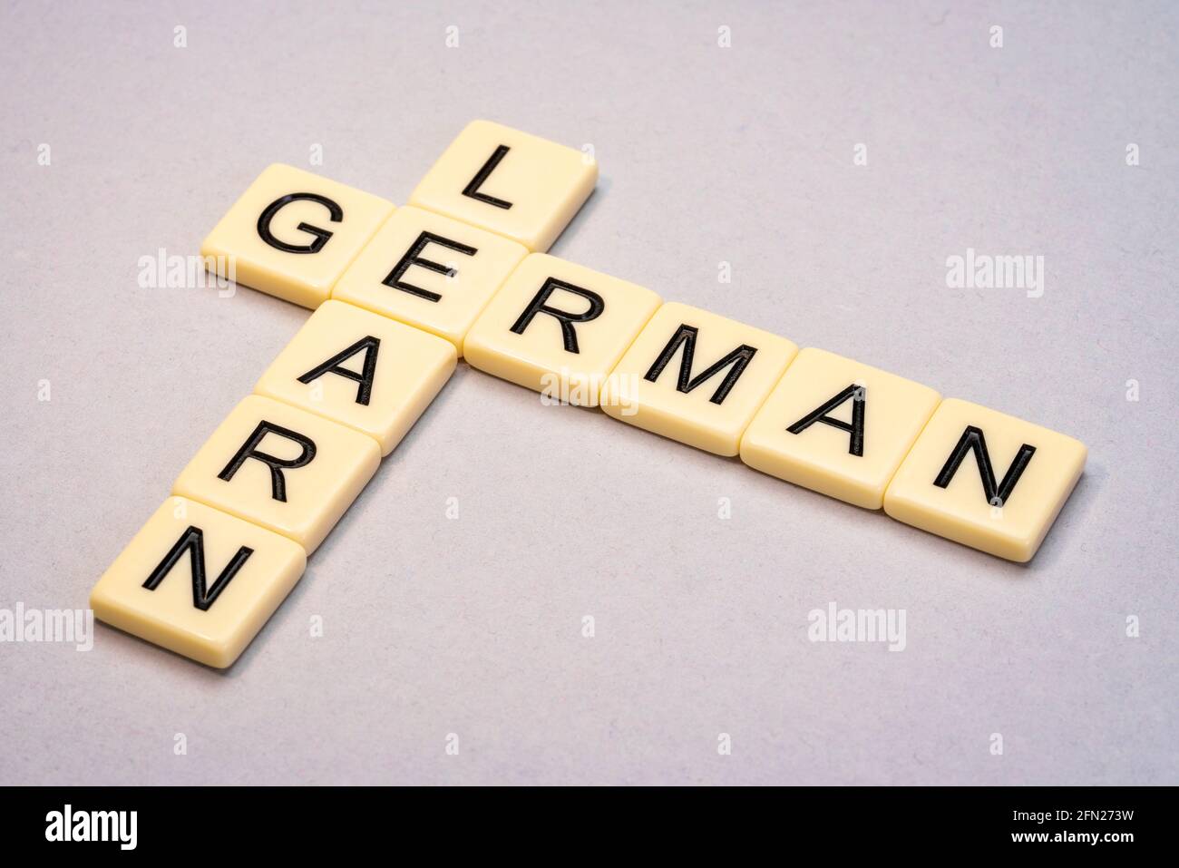Lerne Deutsch Kreuzworträtsel in Elfenbein Buchstaben Kacheln gegen gelb strukturiert Papier Stockfoto