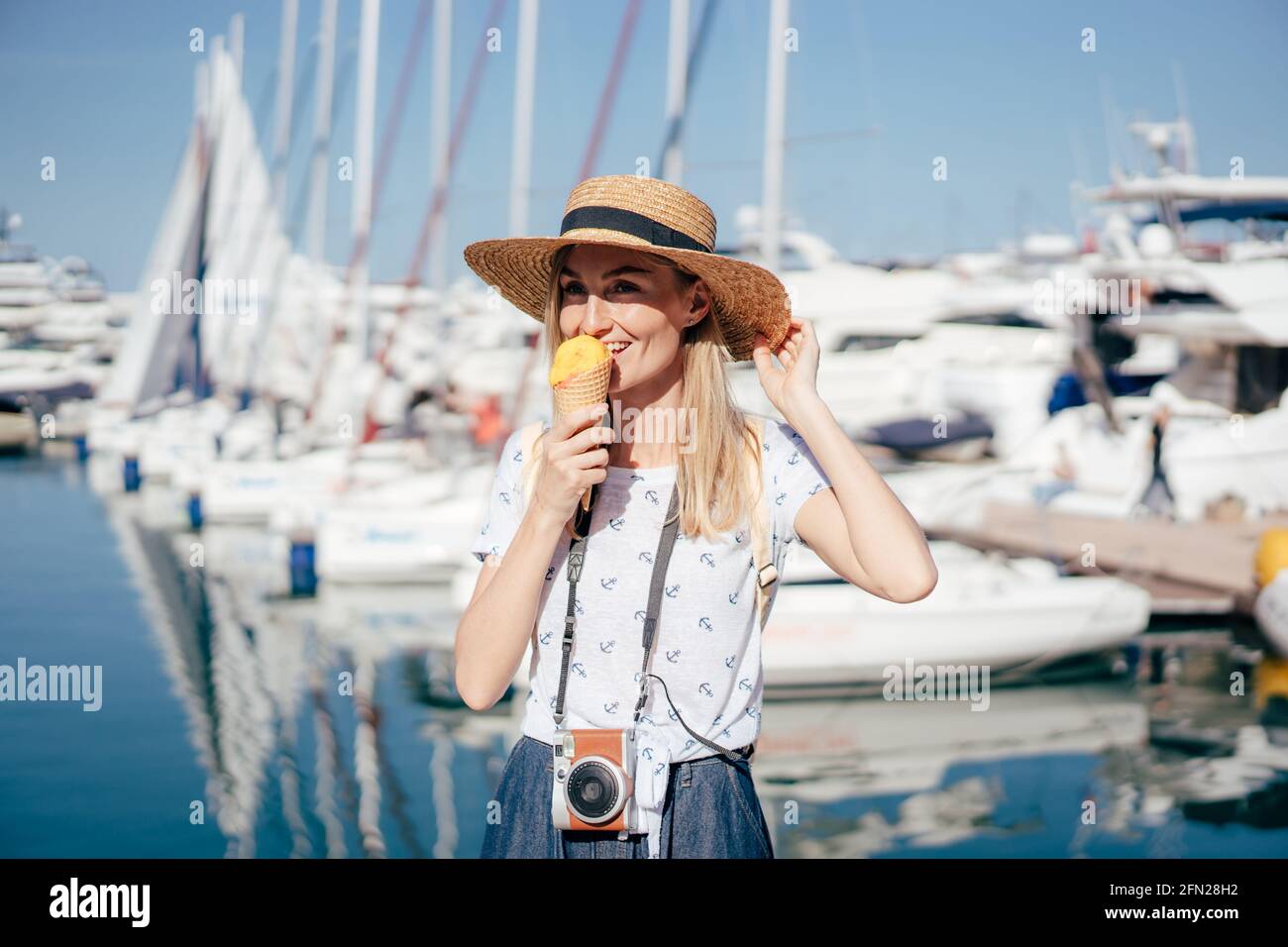 Lustiges Porträt einer Frau im Hafen, die Eiskegel isst. Glückliches Wochenende eines jungen Reisenden. Stockfoto