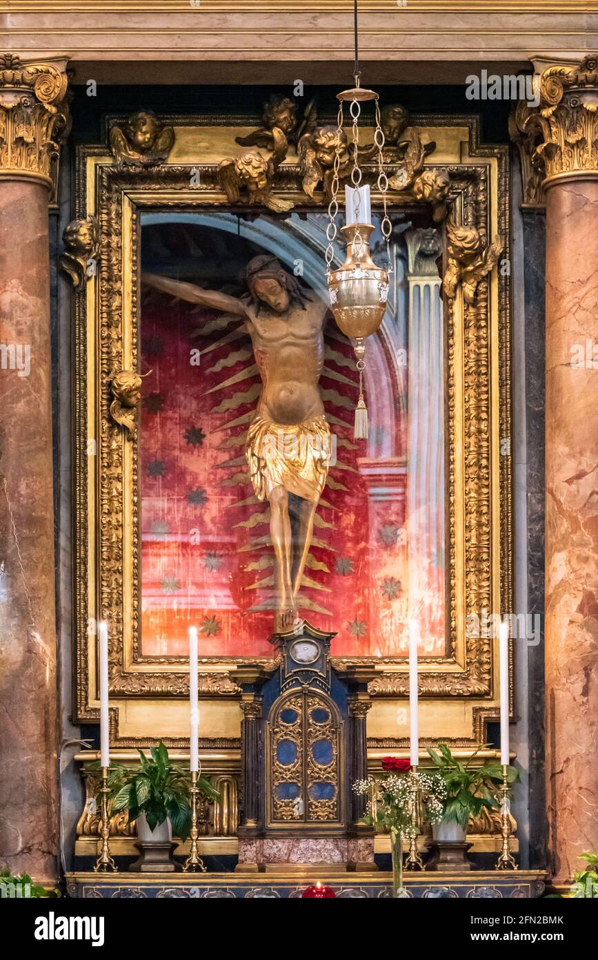 Nahaufnahme eines alten hölzernen Kruzifixes, das hinter einem Glas aufbewahrt wird Die Mauer in der katholischen Kirche in Rom Stockfoto