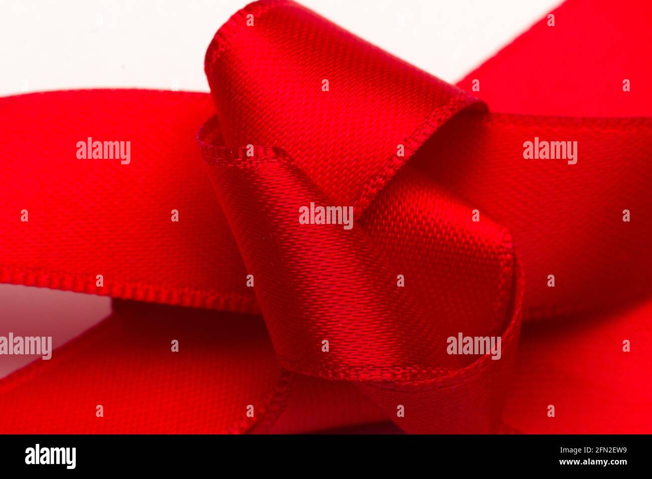 Knoten der roten Farbe, erster Begriff des Knotens auf weißem Hintergrund. Bogenknoten zum Dekorieren von Jubiläumsgeschenken. Stockfoto