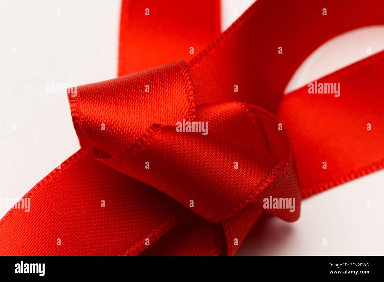 Knoten der roten Farbe, erster Begriff des Knotens auf weißem Hintergrund. Bogenknoten zum Dekorieren von Jubiläumsgeschenken. Stockfoto