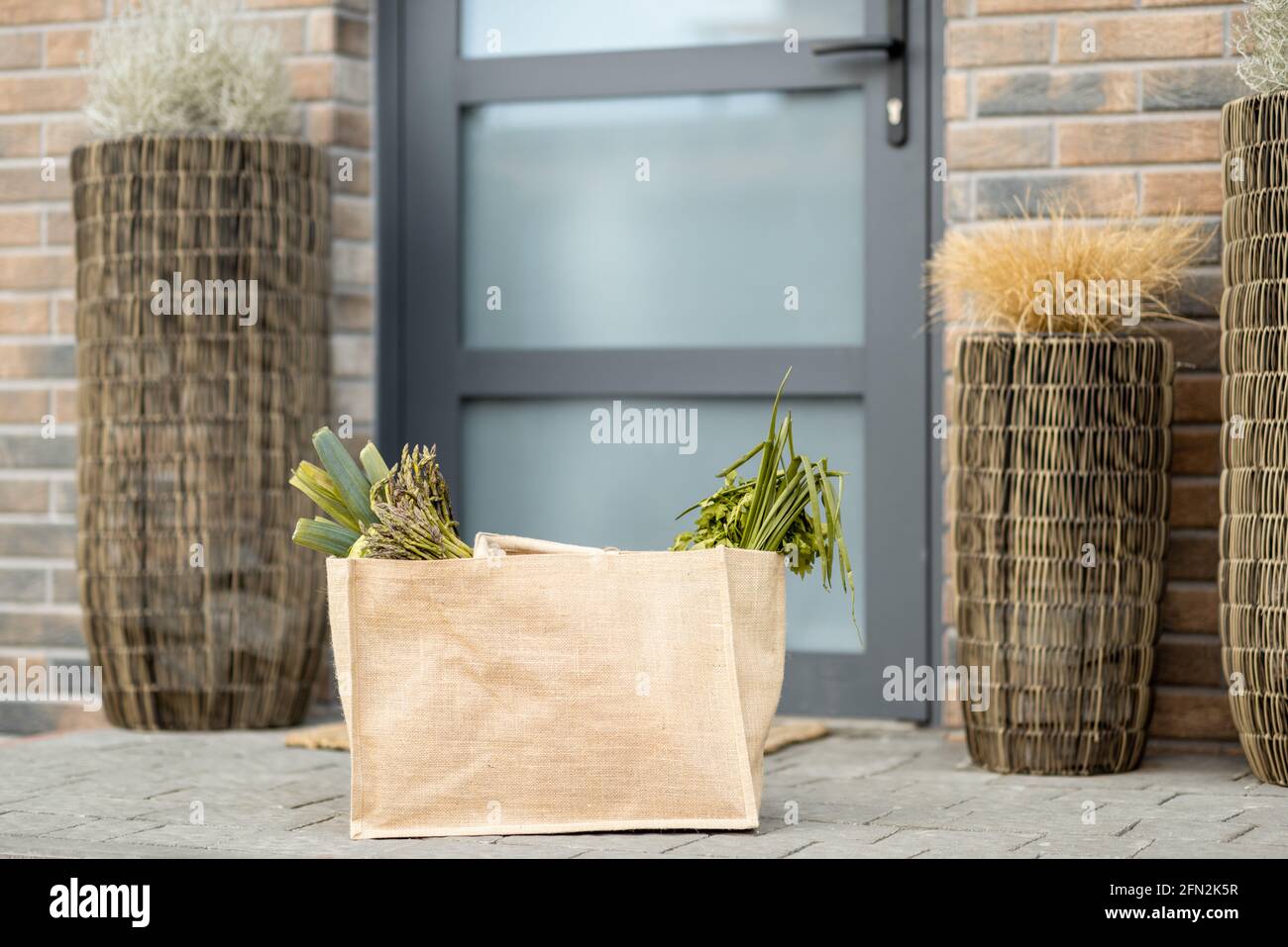 Einkaufstasche mit frischen Produkten aus dem Lebensmittelgeschäft vor der Haustür vor der Haustür. Kontaktloses Lieferkonzept. Stockfoto