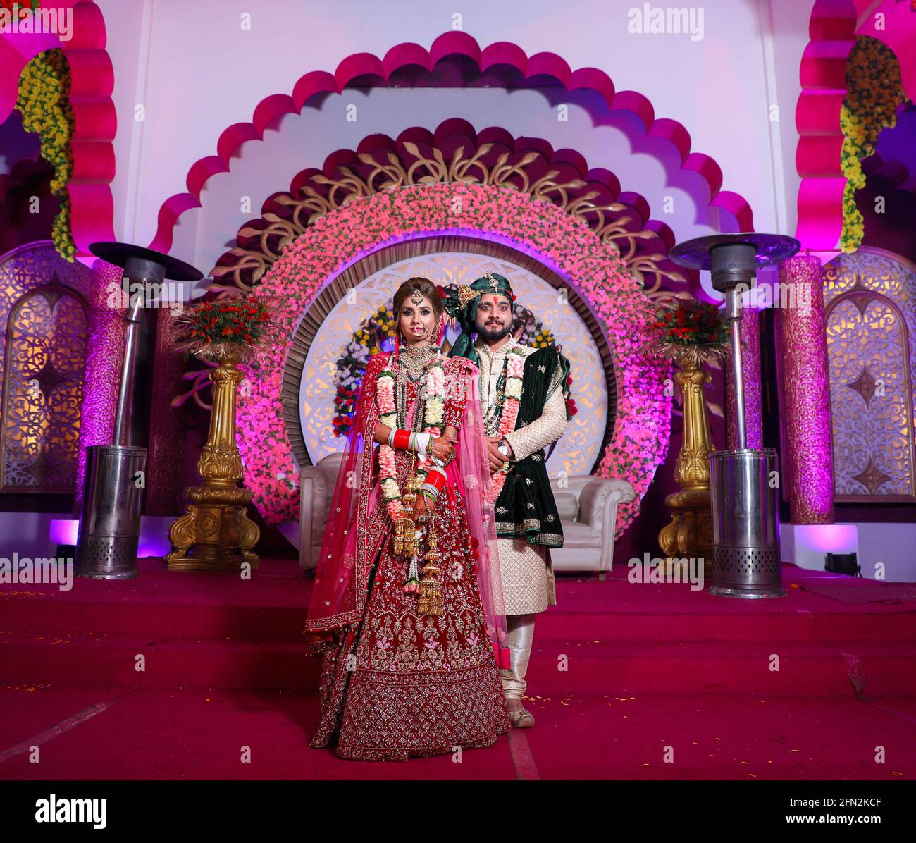 Wunderschöne atemberaubende indische Braut und Bräutigam tragen traditionell Kleid posieren auf ihrer Hochzeitszeremonie. Stockfoto