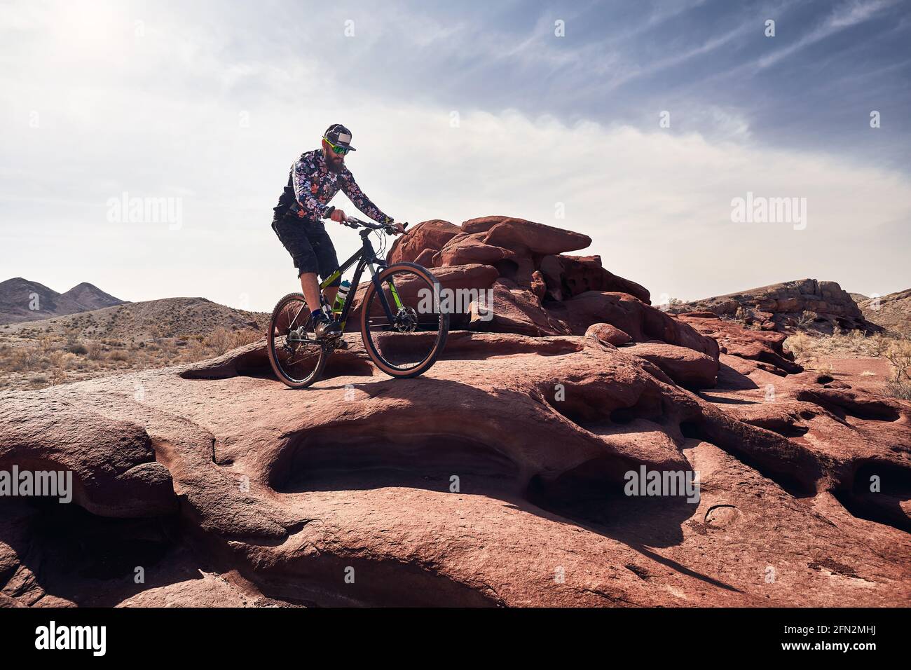 Reiter mit Bart fährt sein Mountainbike im Wüstenvulkanischen Berg im Nationalpark Altyn Emel in Kasachstan. Extremsport und Outdoor recreati Stockfoto