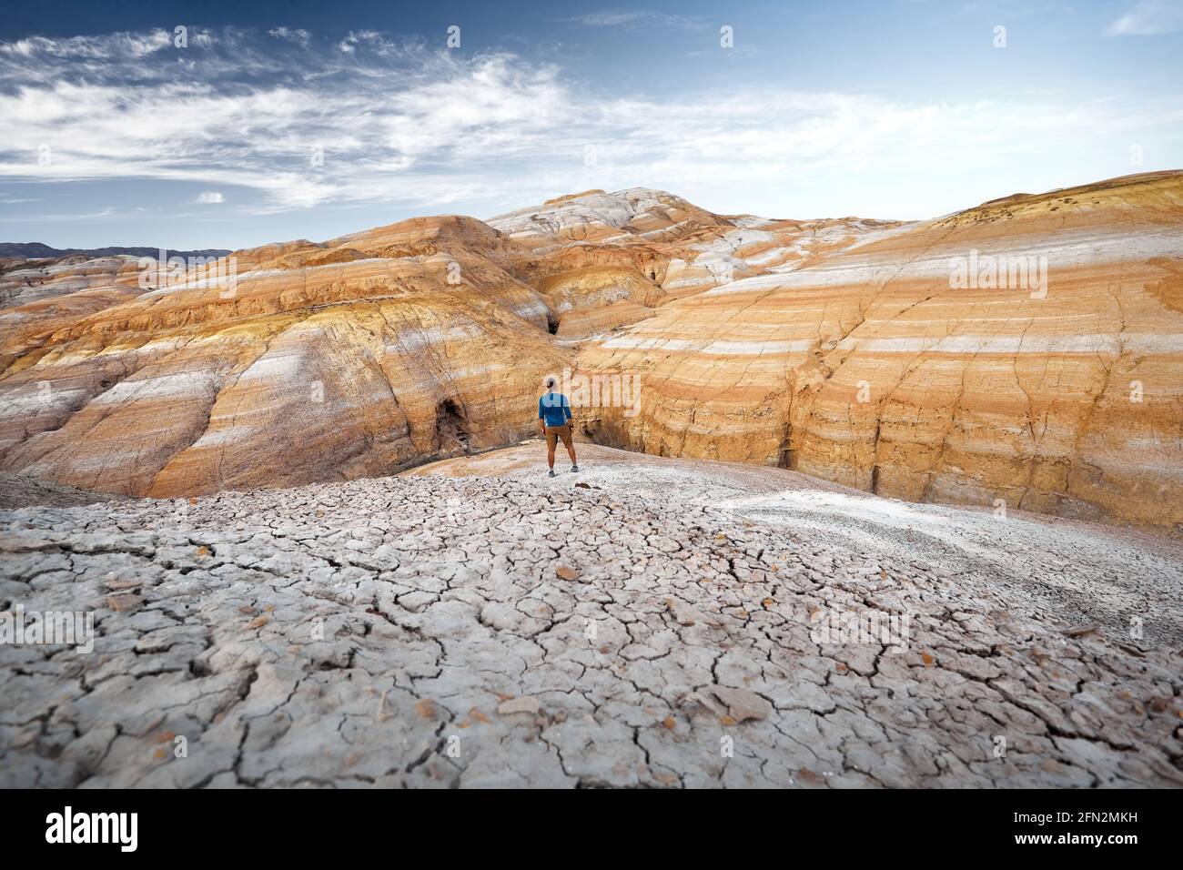 Wanderer in blauem Hemd bei Dürre geknackt Erde rot gestreift Wüstenberge in Kasachstan Stockfoto
