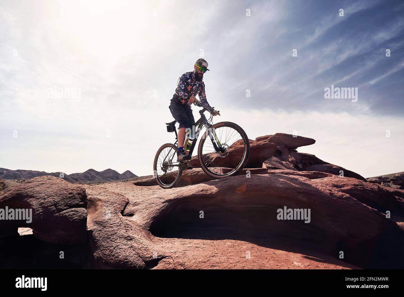 Reiter mit Bart fährt sein Mountainbike im Wüstenvulkanischen Berg im Nationalpark Altyn Emel in Kasachstan. Extremsport und Outdoor recreati Stockfoto
