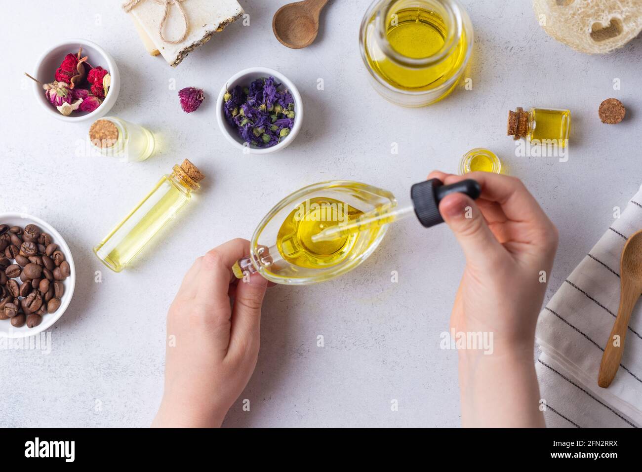 Natürliche Bad-Accessoires, Bio-Spa- und Kosmetikprodukte. Hand tropft Öl. Flach liegend. Stockfoto