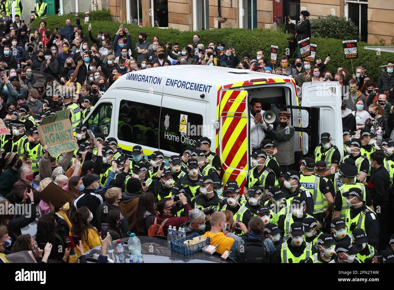 Einer von zwei Männern wird in Begleitung von Mohammad Asif, dem Direktor der Afghan Human Rights Foundation, in der Kenmure Street, Glasgow, von Demonstranten umgeben, von der Rückseite eines Van für Einwanderungsbehörden entlassen. Bilddatum: Donnerstag, 13. Mai 2021. Stockfoto