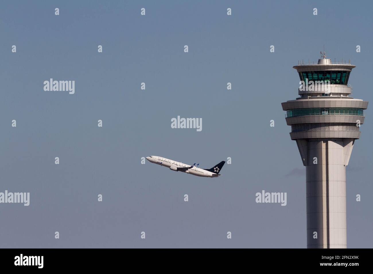 Ein All Nippon Airways (ANA) Boeing 737-800-Linienflugzeug, in Star Alliance-Lackierung, das hinter dem Flugsicherungsturm am Flughafen Haneda abfliegt. Stockfoto