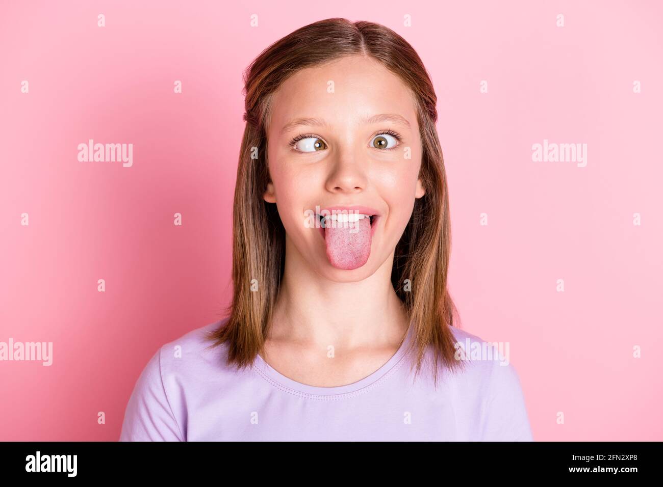 Foto von lustigen kindischen Teenager-Mädchen machen funky Face Stick Zunge aus isoliert auf pastellrosa Hintergrund Stockfoto