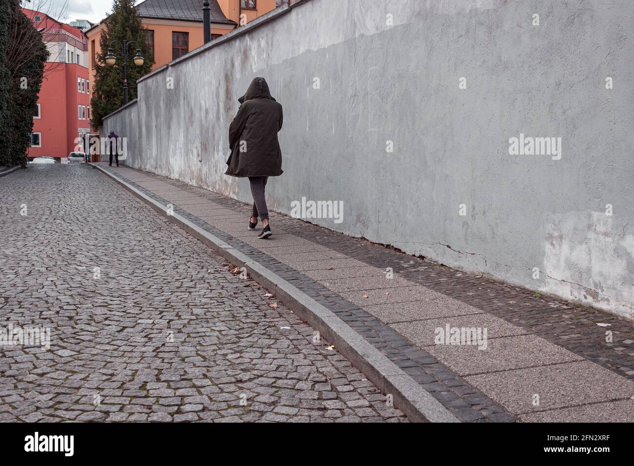 Mann in einer schwarzen Kapuzenjacke, der auf der Straße unterwegs ist Stockfoto